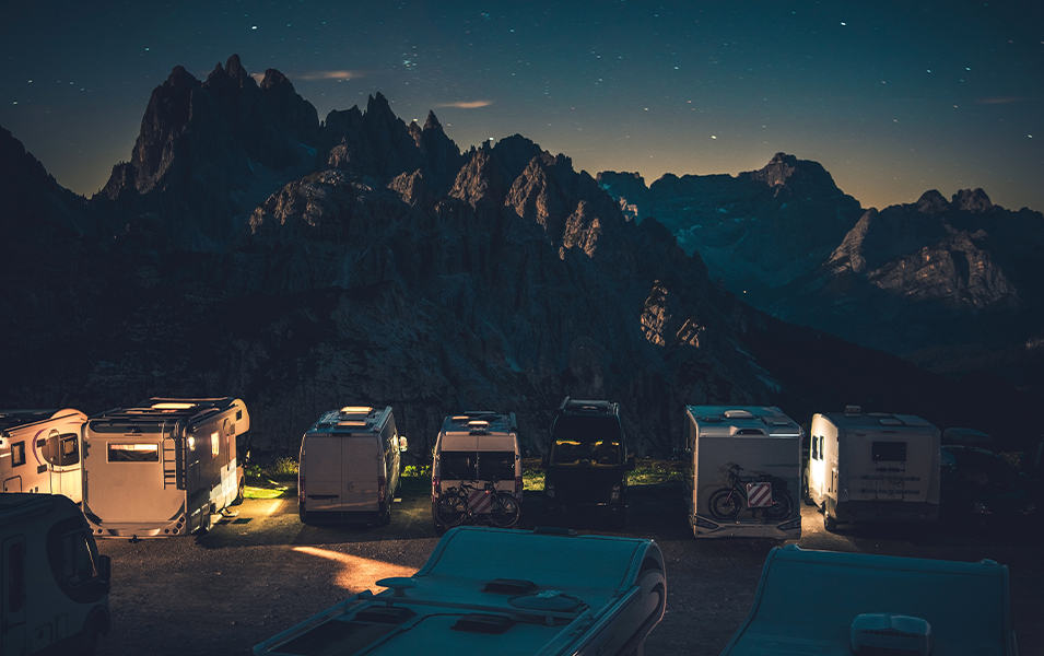 An RV campsite at night over looking a rugged mountain landscape. 