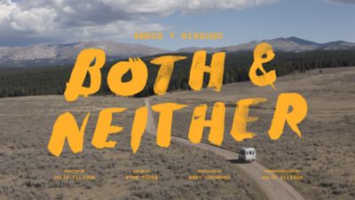 AMBOS Y NINGUNO subhead, Both & Neither film title card. Directed by Julie Ellison, Edited by Ryan Scura, Produced by Andy Cochrane, Cinematography by Julie Ellison. Image of a van on a dirt road driving towards pine and mountains.