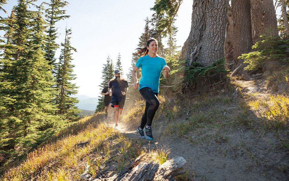 A trail runner comes around the corner in a scenic forest setting. 