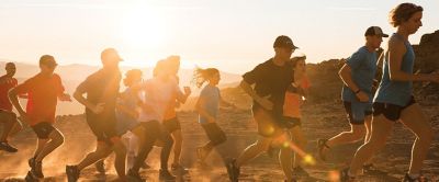 A group of trail runners is pictured at sunset running in the soft light. 