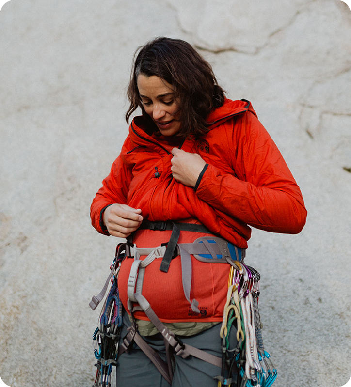 Miranda looking at her pregnant belly while taking a break from climbing
