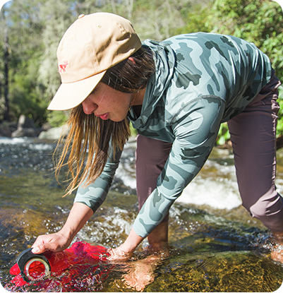 close up of a backpacker filling up her water from a stream