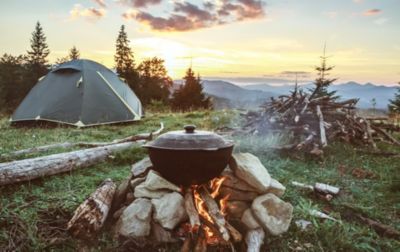 A hiker has set up a smart camp, with a tent that's perfectly staked out, and far enough from the campfire for safety.