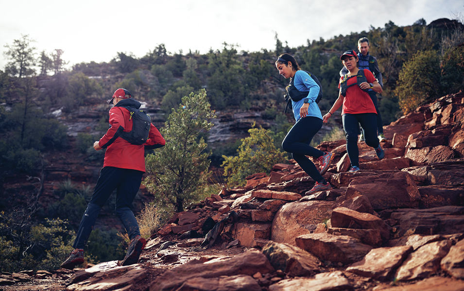 Four trail runners running down a rocky hill. 
