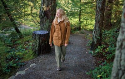 A young woman strolls in solitude through a dense, green forest. 