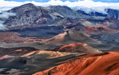 High above the cloudbank, the rich earthtones of a volcanic landscape stretches out in Haleakalā National Park. 