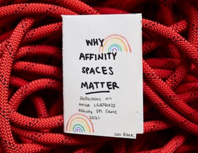 "WHY AFFINITY SPACES MATTER. Relfection son AMGA LGBTQIA2S Affinity SPI Course 2021 by Lou Bank" handmade booklet sitting on top of a pile of red climbing rope.