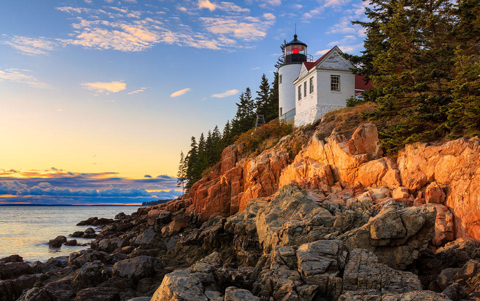 A lighthouse towers over the ocean shore in Maine’s Acadia National Park.