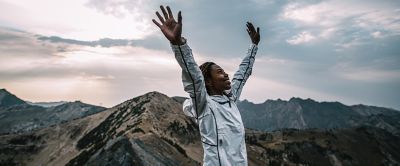 Woman with arms raised at the top of mountain. 