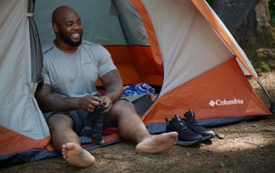Man sitting in Columbia Tent putting on socks and Columbia hiking shoes.