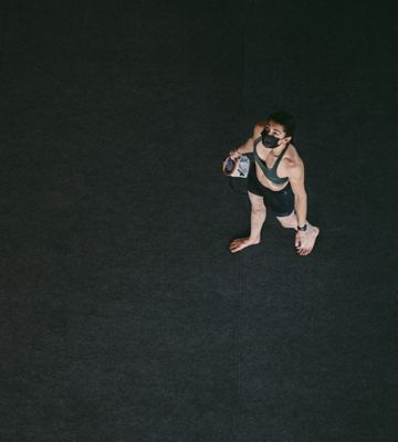 Birds eye view of Kyra on the gym floor, looking up with chalk bag in hand