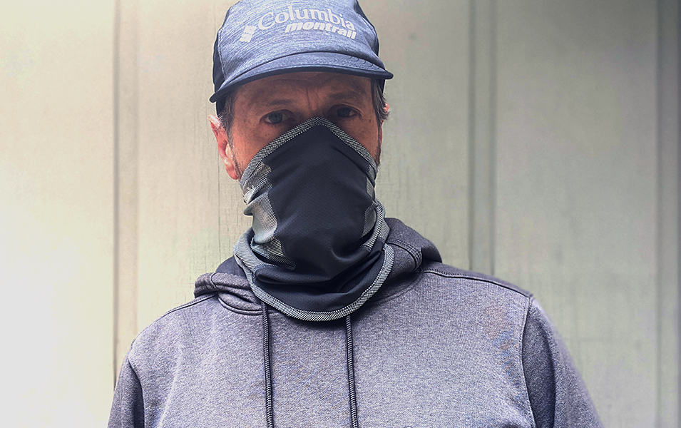 Man wearing a hat and neck gaiter over his nose. 