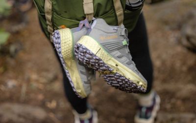 Une paire de bottes de randonnée Columbia Sportswear suspendues à une sangle de sac à dos.
