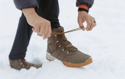 Randonneur laçant des bottes Columbia Sportswear dans la neige.
