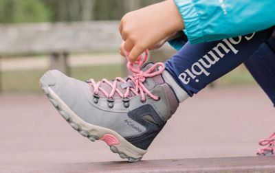 Une personne ajustant les lacets d'une chaussure de randonnée Columbia Sportswear.