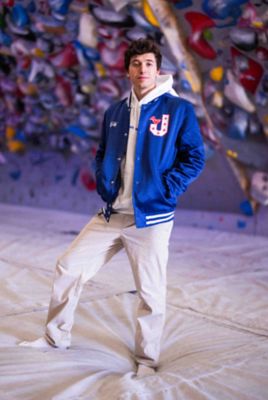 Jesse stands with his Varsity Jacket on in the climbing gym.
