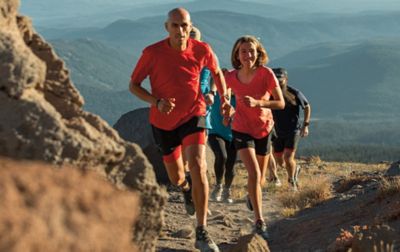 Several people of different ages run up a dirt trail. 