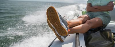 An angler kicks back on a fishing boat with her feet up wearing a pair of Columbia Sportswear PFG fishing shoes.