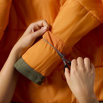 Scissors clipping the seam of a jacket cuff to extend the sleeves