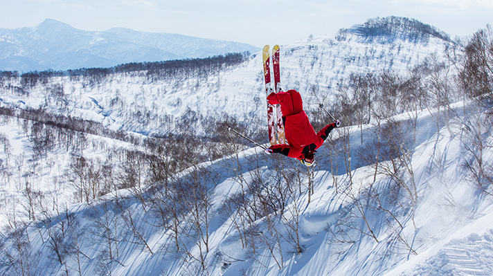 Alex Ferreria in midair doing a backflip on a mountain slope. 