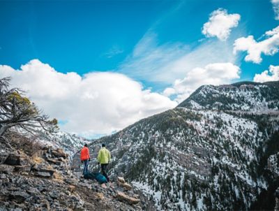 A pair of hikers walk through the mountains on a scenic trail. 