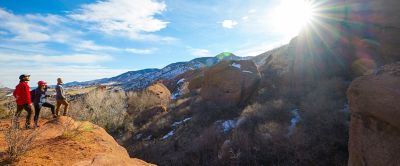 A trio of hikers stands on top of a gorgeous cliff looking out at the scenery. 
