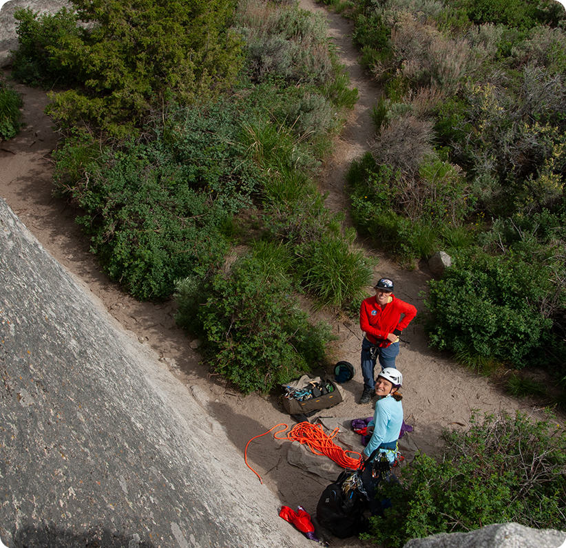 Birds eye view of two smiling participants on the ground from the rockface
