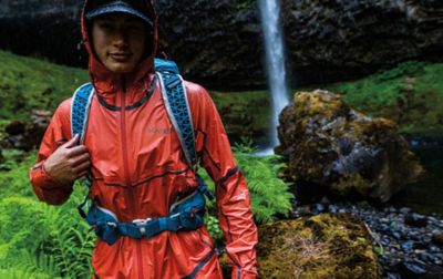 A man hikes through a wet scenic rainforest wearing a waterproof jacket.
