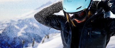 Woman putting her hood up on a snowy ski hill.