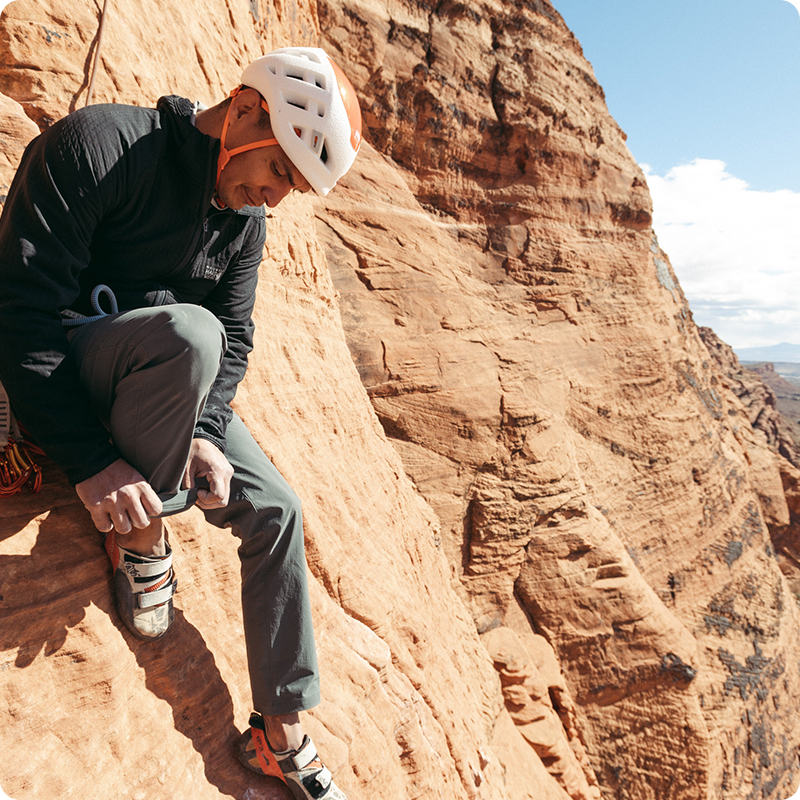 A climber adjusting his climbing shoes