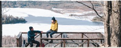 A couple talking on a deck overlooking an icy lake