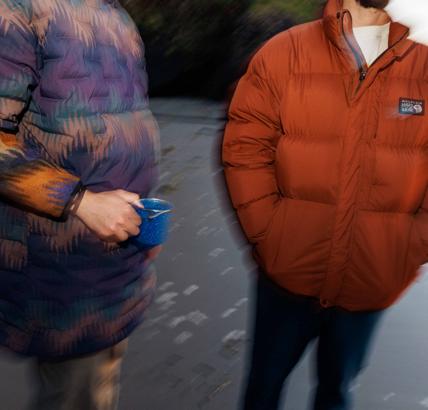 Semi blurry photo of two friends chatting while camping. Close up of their jackets.