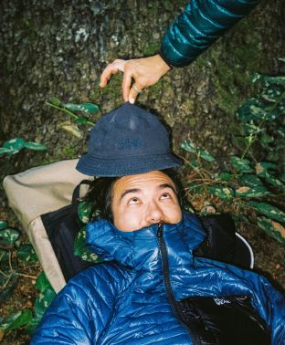 Mischievously holding up a bucket hat over another camper's head, posing silly for the camera.