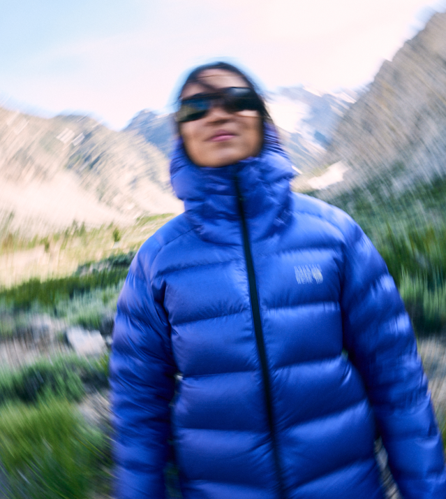 Blurry shot of a woman in a down jacket smiling at the camera.