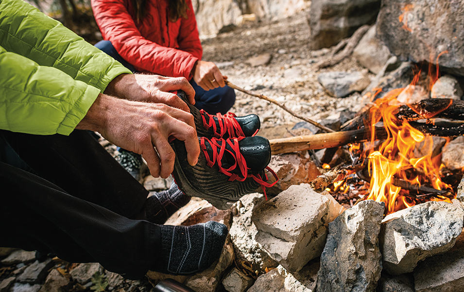People around a campfire drying out shoes. 