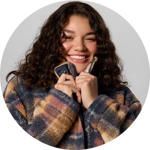 A smiling woman getting cozy in fleece.