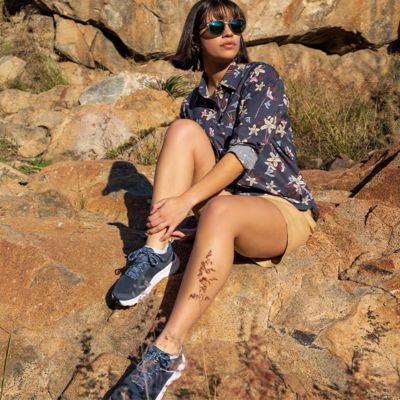 A woman in Columbia hiking shoes sitting on rocks. 
