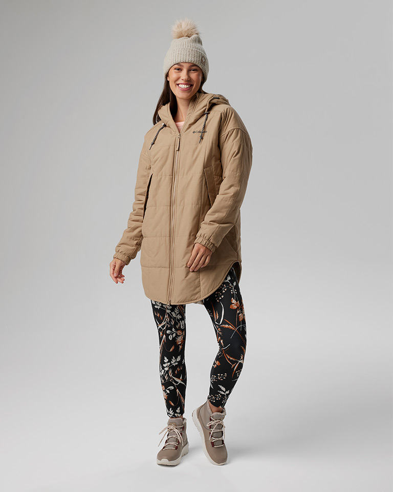 Outfit 7: knit pom pom beanie, long tan insulated jacket over a pink waffle-knit top and floral print leggings, tan boots.