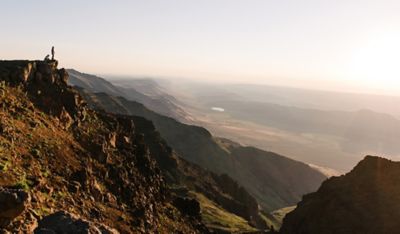 Two hikers on a distant cliff.