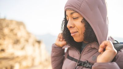 MHW ambassador Genevive Walker pulls down on her hoody, stretching significantly, while hiking outside of Salt Lake City