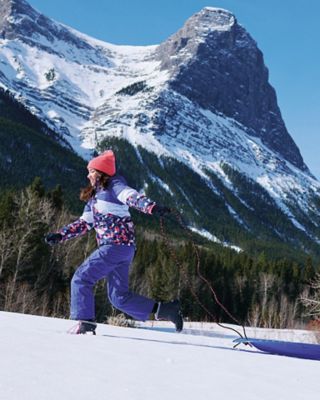 A woman having fun in the snow with a beautiful mountain in the background.