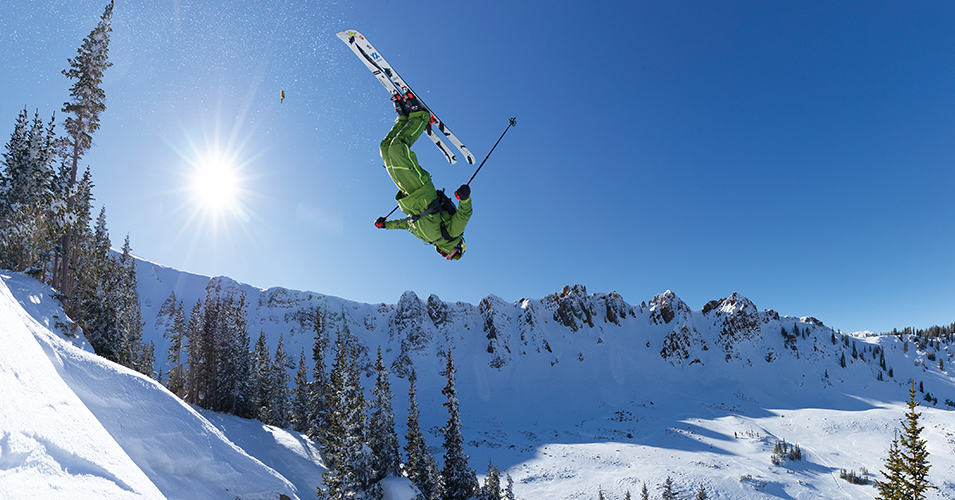 A skier doing a flip on a bluebird day.