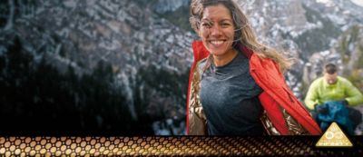 A smiling woman wearing a metallic gold-lined Omni-Heat Infinity jacket outdoors. 