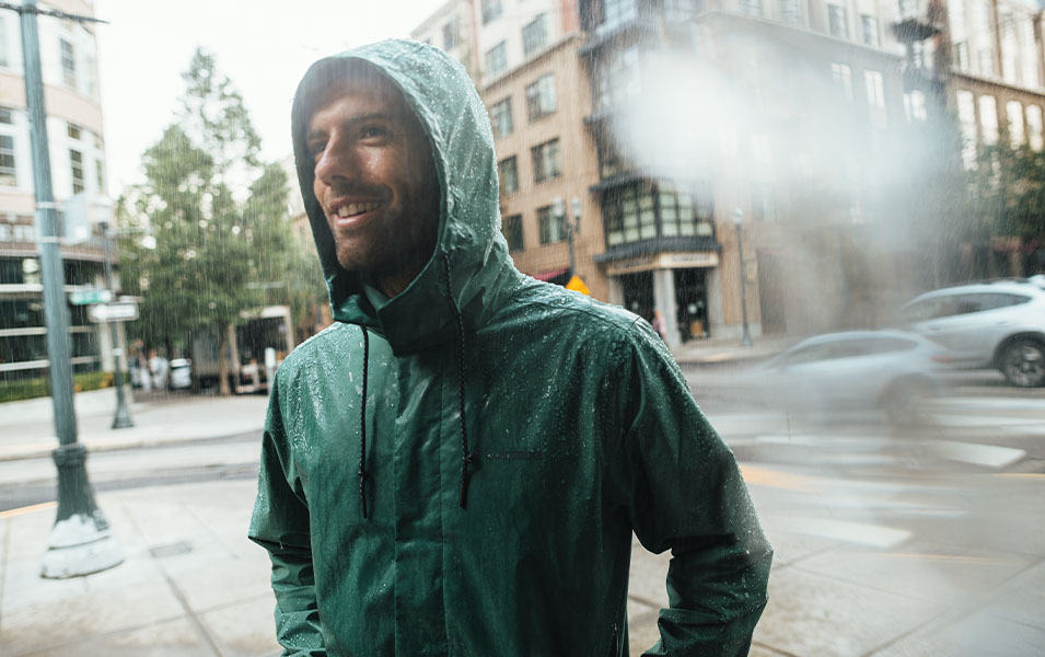 Man standing on a street corner in the rain. 