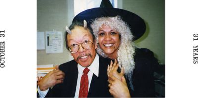 OCTOBER 31 / 31 YEARS typed out on either side of an archive image of two MHW employees wearing vampire costumes.
