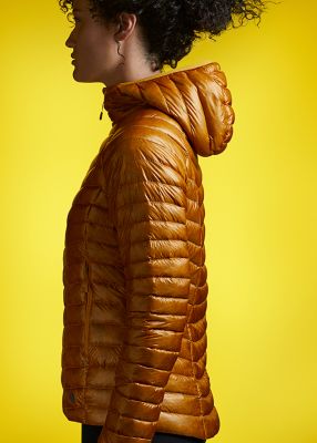 Side profile portrait in studio wearing the Ghost Whisperer/2 Down Hoody with a tonal yellow background to match the jacket