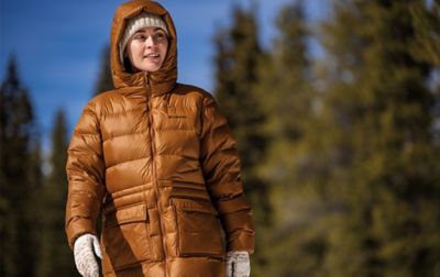 Femme dans une parka gonflée orange Columbia avec la capuche relevée.