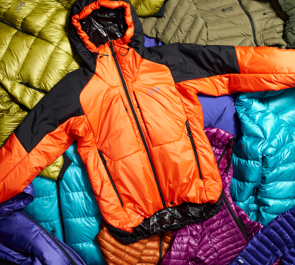 Lay down of several down and synthetic jackets, with a Compressor jacket on top.