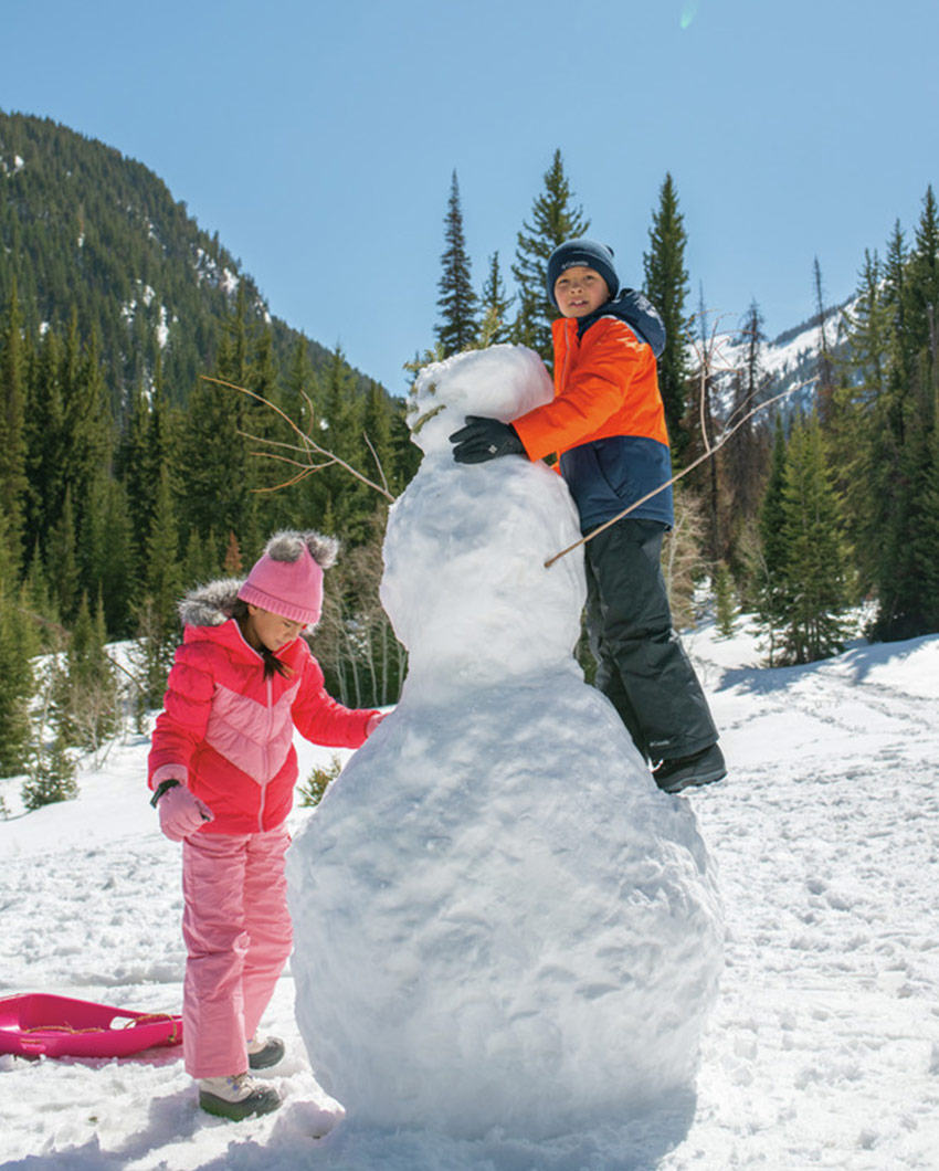 Two cute kids building a snowman.