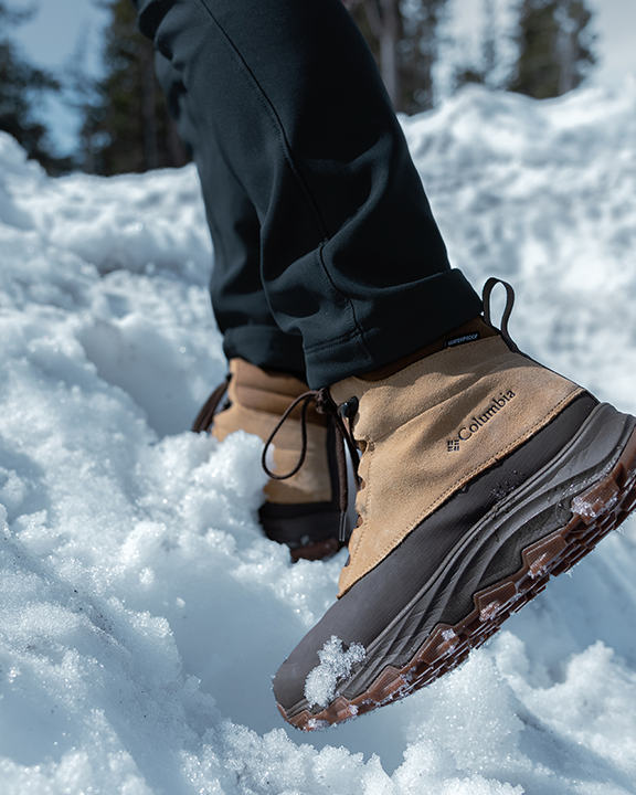 A zoomed-in shot of a person's feet in winter boots walking through the snow.
